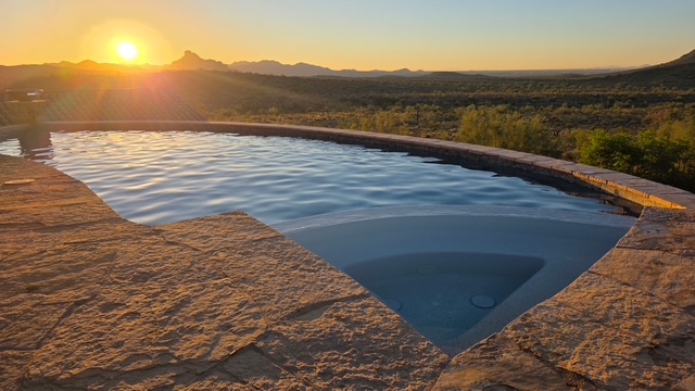 Infinity-edge pool finished by Infiniti Pool Service, overlooking the Arizona desert at sunset